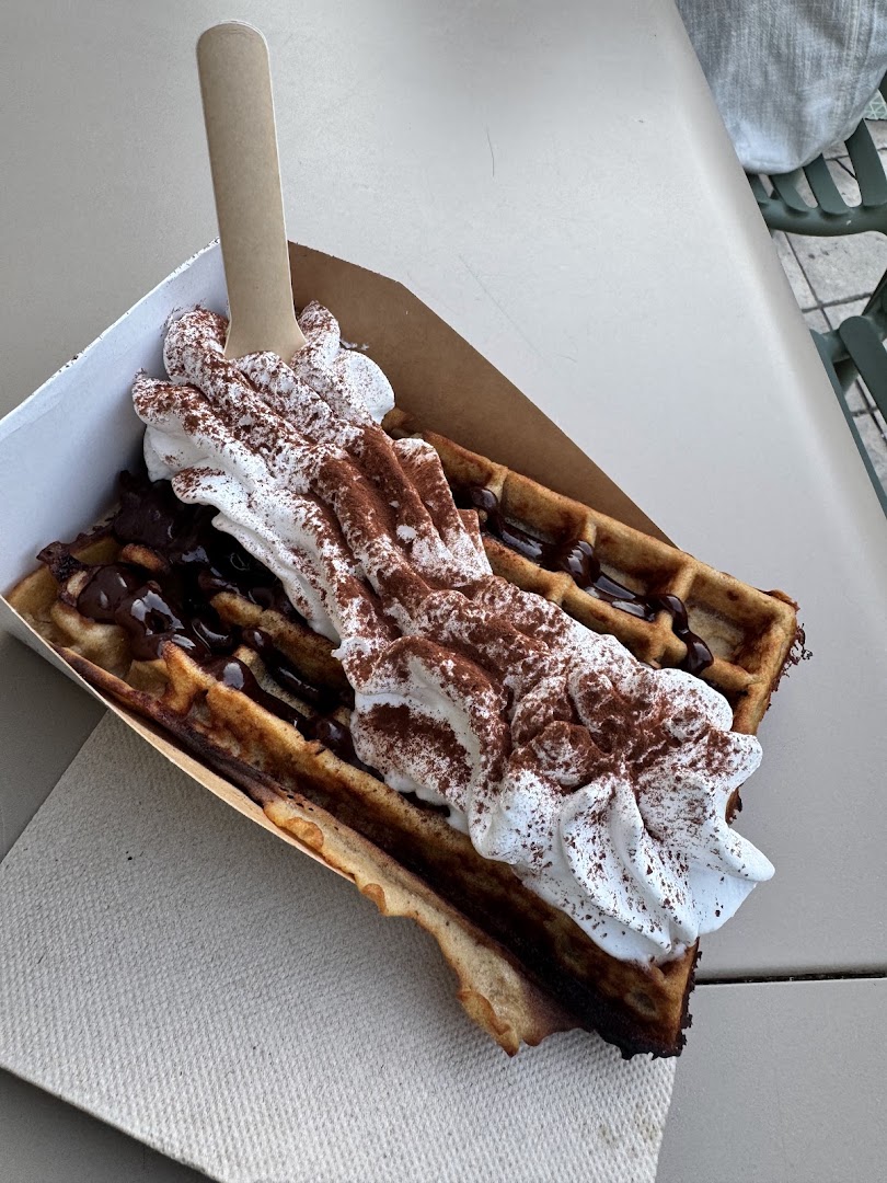 Une gaufre avec glace, crème fouettée et sauce au chocolat